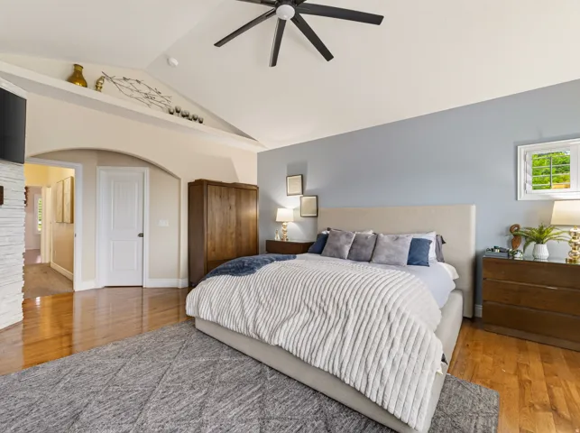 Vaulted ceiling, ceiling fan, arched doorway, hardwood flooring, window with white shutters