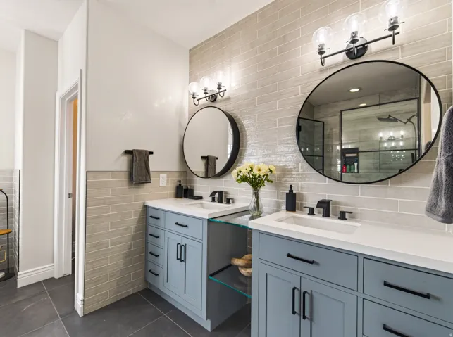 Dual vanities with white countertops, matte black faucets, and round mirrors