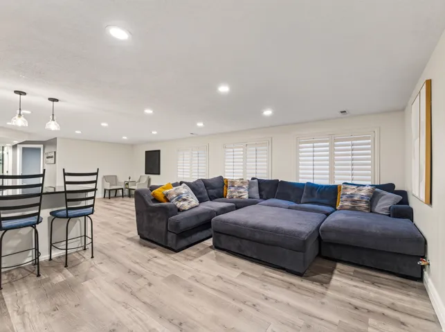 Recessed lighting, wood-finish flooring, white walls, built-in counter bar, and plantation shutters