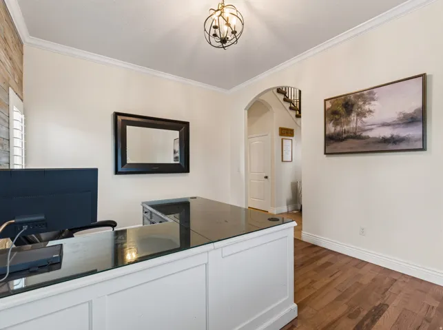 Hardwood-finish flooring, crown molding, and an arched doorway