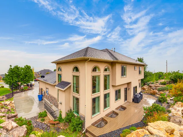 Stucco exterior residence with arched windows, a composition shingle roof, and a multi-level deck