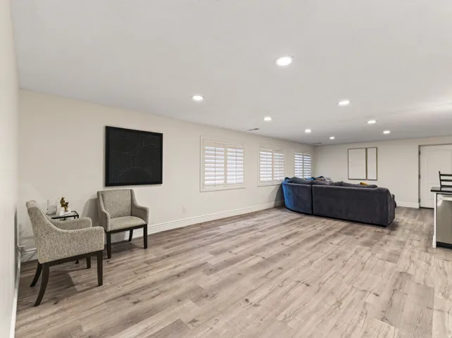Expansive room featuring wood-finish flooring, recessed lighting, and multiple windows with plantation shutters