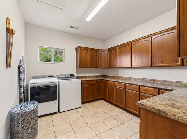 Tile flooring, wood cabinetry, ample counter space, window, and overhead lighting