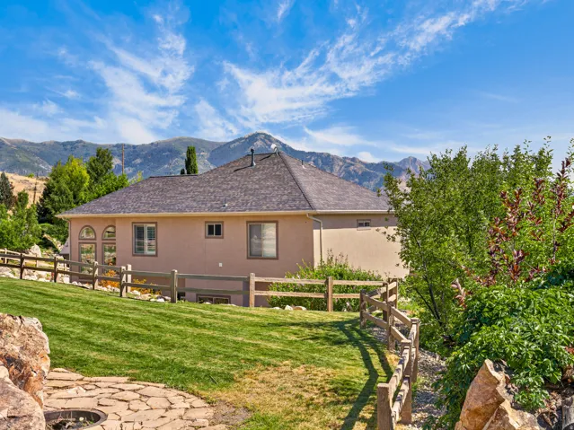 Expansive backyard with a manicured lawn, established landscaping, and a wood split-rail fence