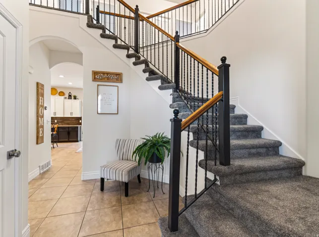 Carpeted staircase with wrought iron balusters and wood handrails