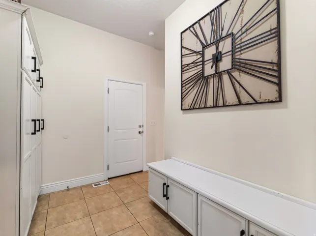 Built-in white cabinetry, white paneled door, and tiled flooring
