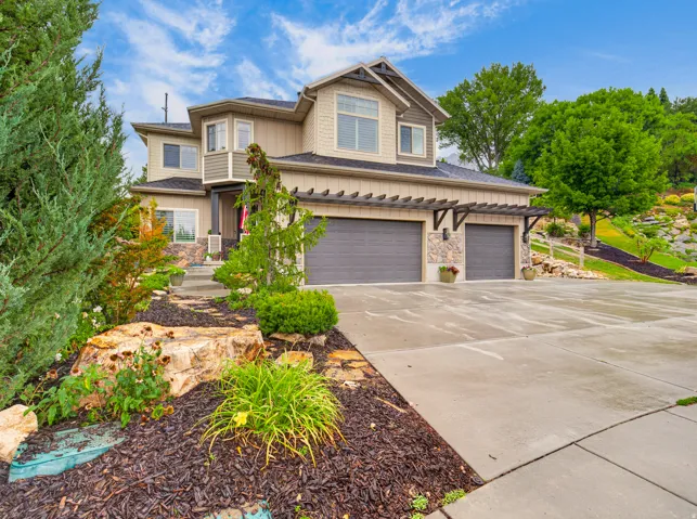 Multi-level dwelling with a two-car garage, stone accents, and decorative pergola
