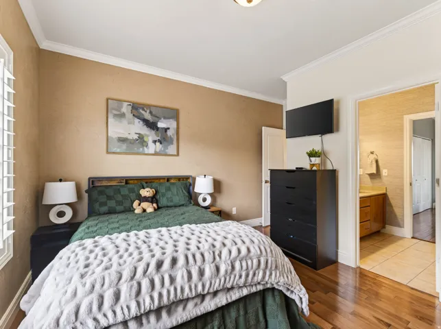 Hardwood flooring complemented by crown molding and a built-in wall-mounted television