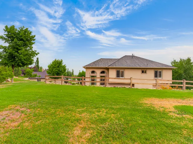 Expansive green lawn with mature trees and a split-rail fence