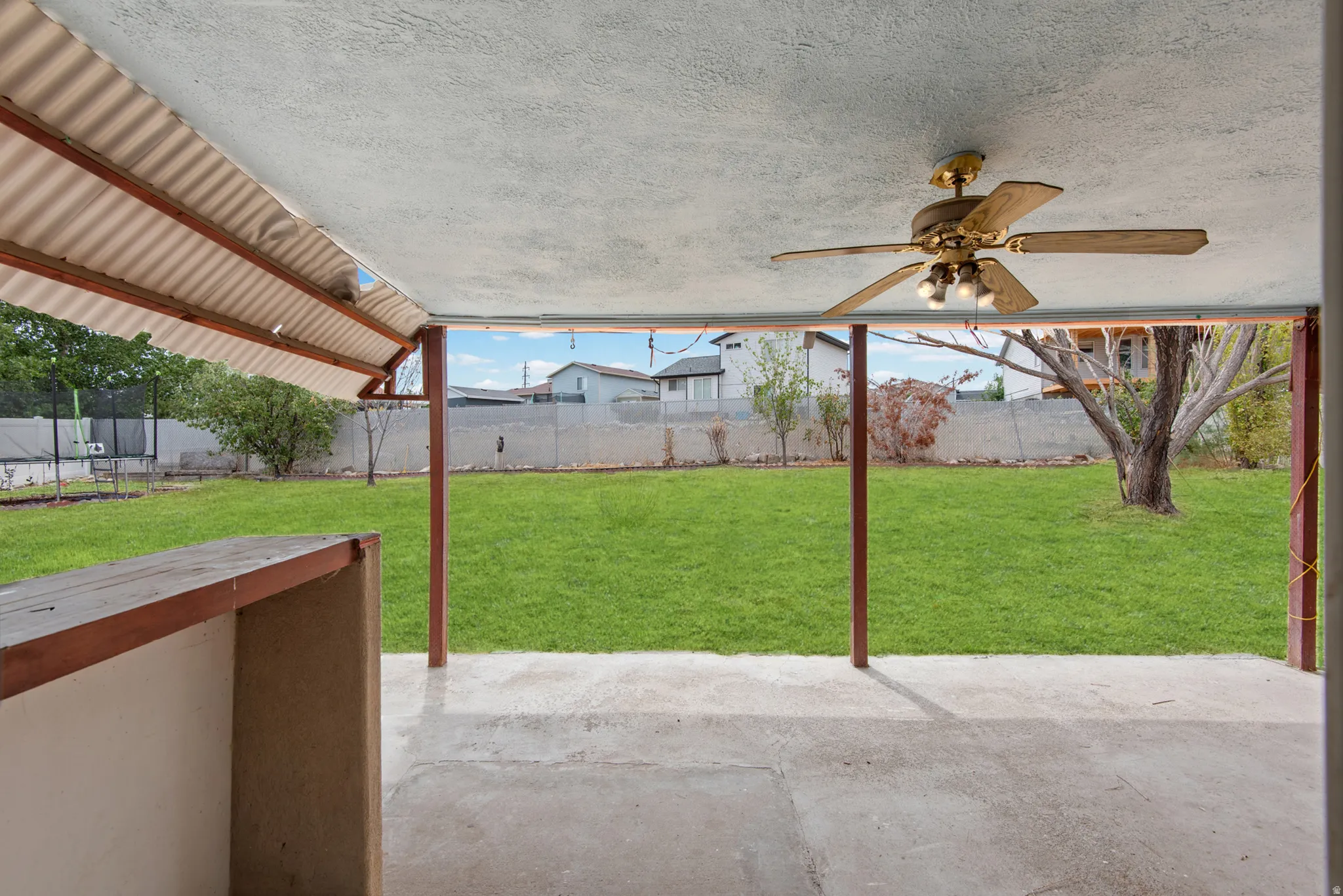 Covered patio with a ceiling fan, concrete flooring, and a corrugated metal roof
