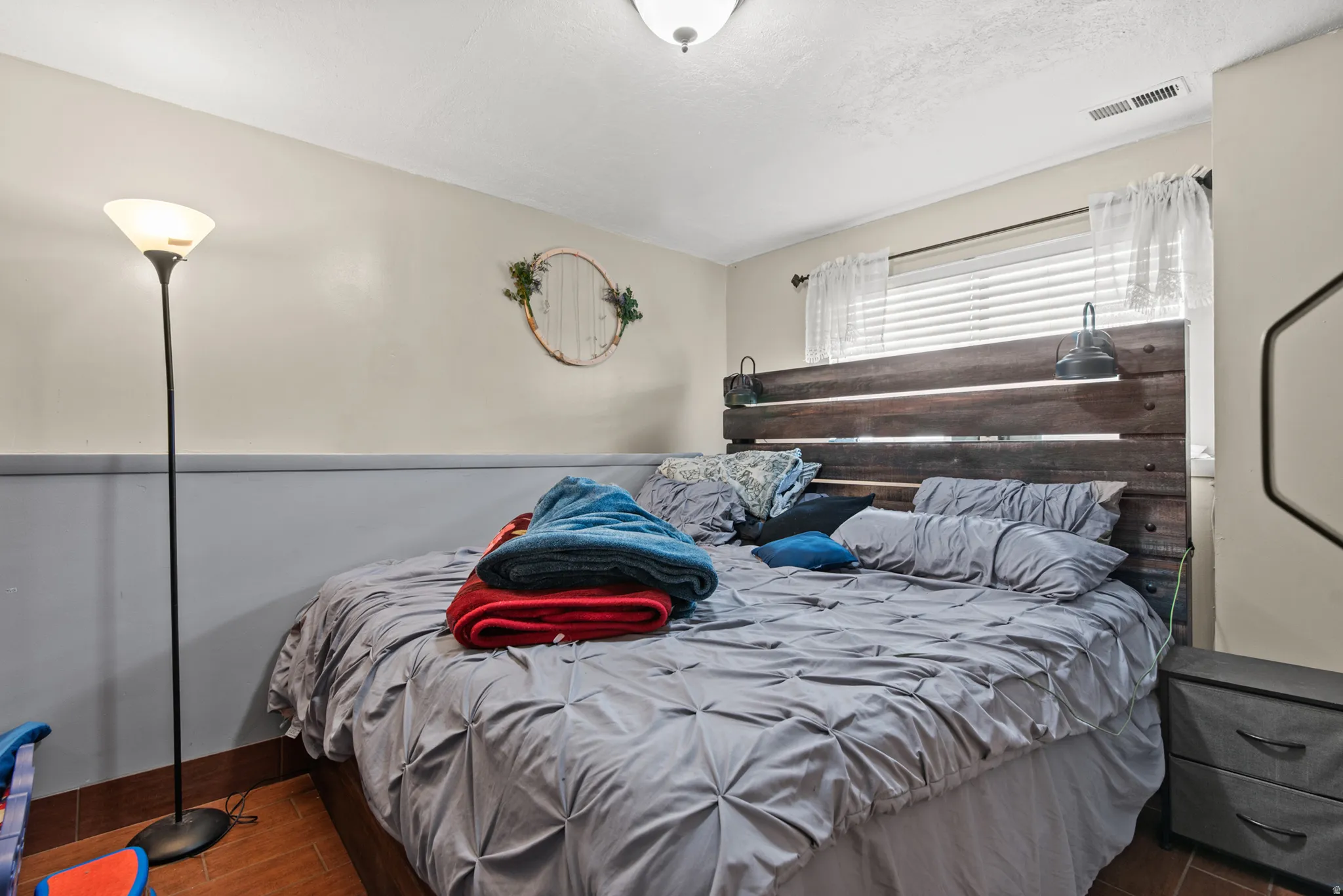 Window with blinds, wood-finish flooring, two-tone wall paint, and a ceiling-mounted light fixture