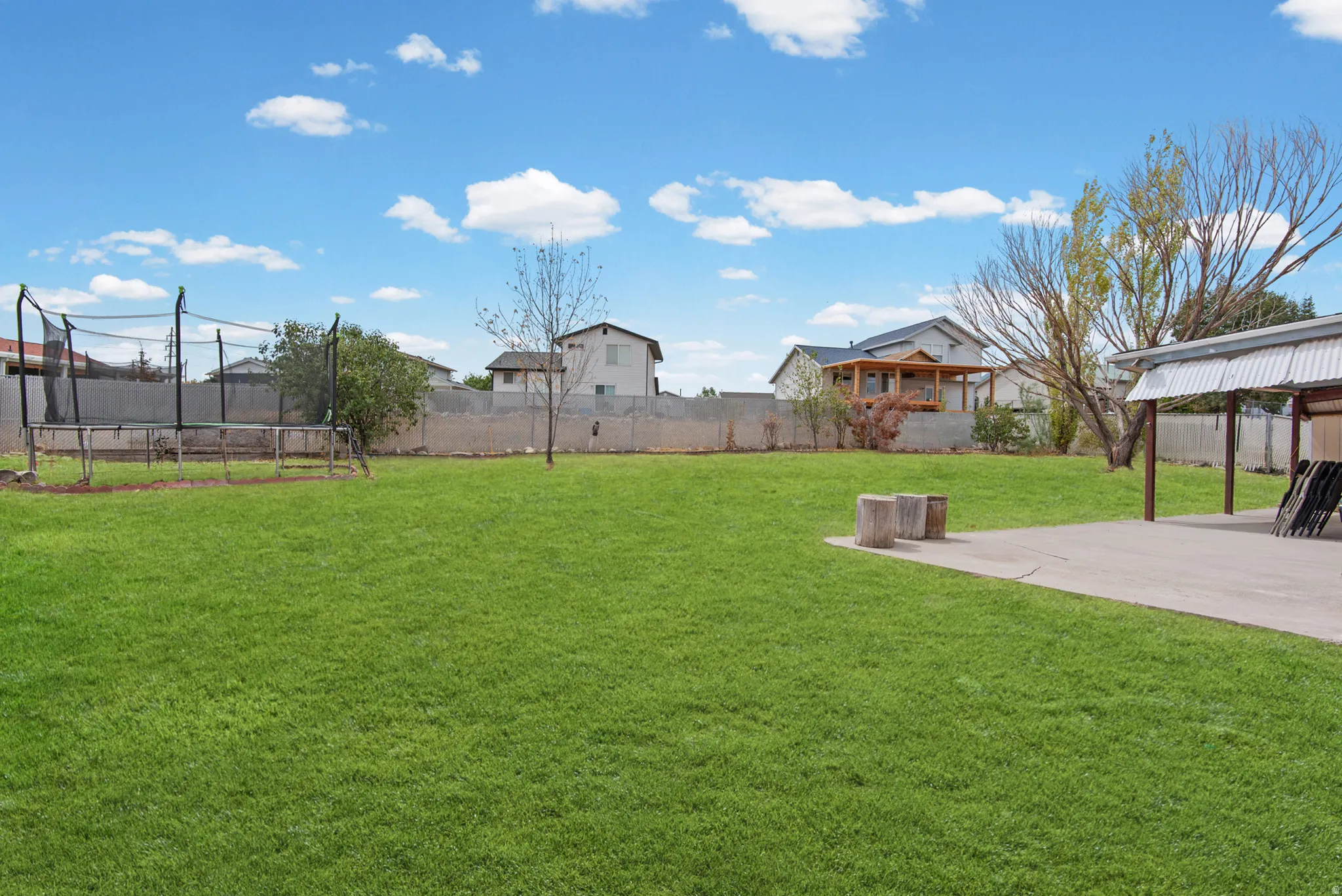 Expansive green lawn with a concrete patio and a covered outdoor structure