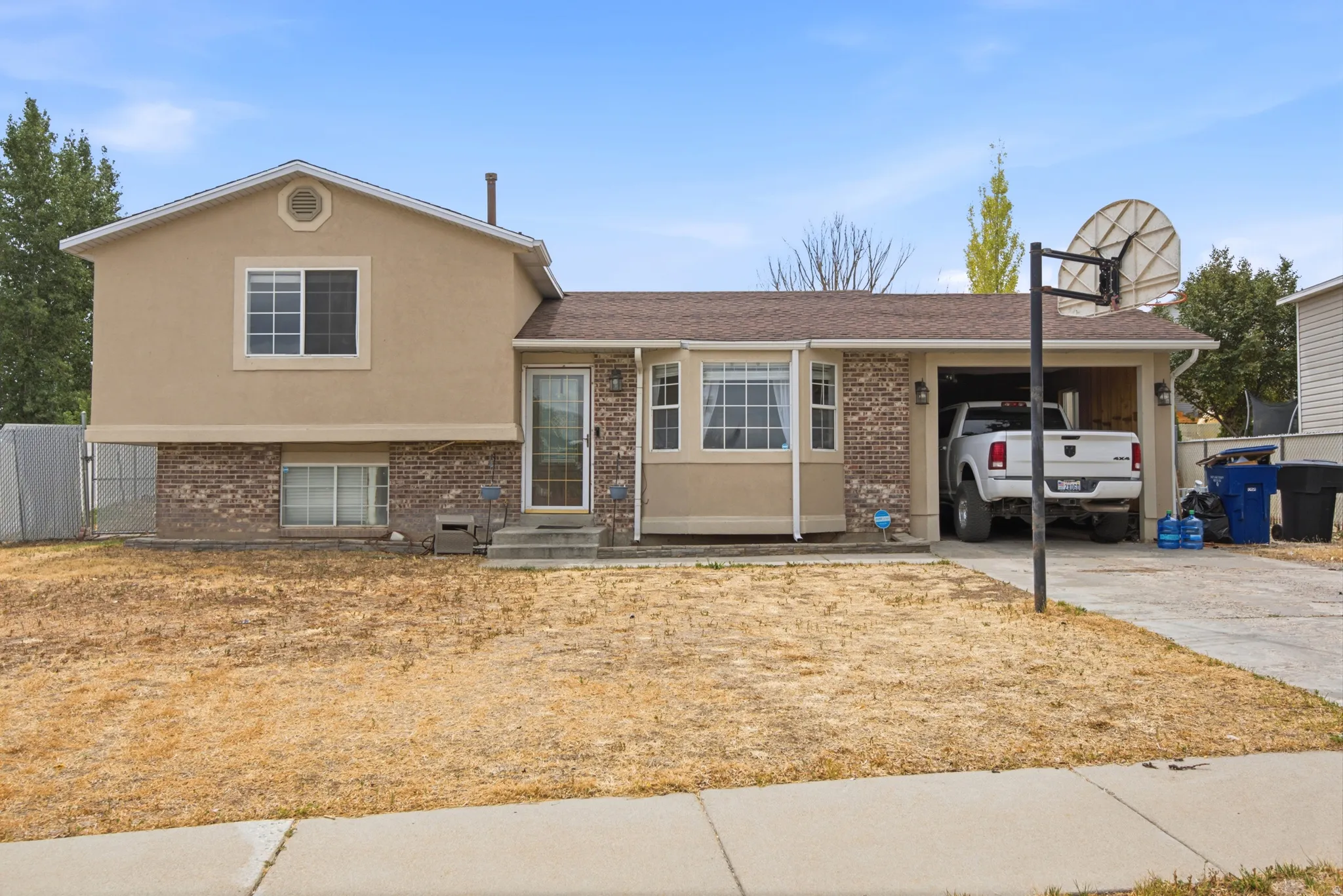 Split-level residence featuring a brick and stucco facade, an attached garage, and a concrete driveway