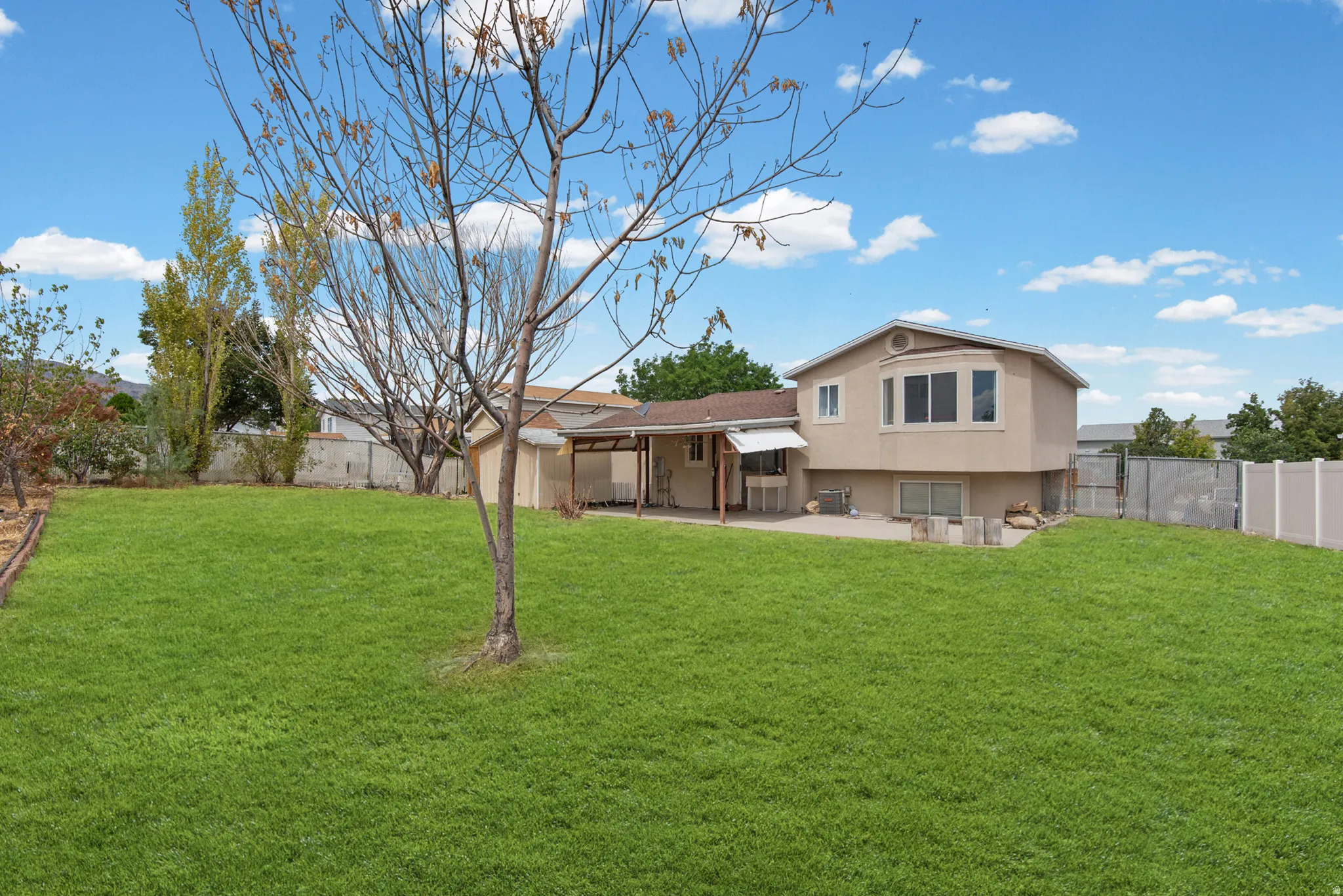 Expansive rear yard featuring a grass lawn, a covered patio, and a privacy fence