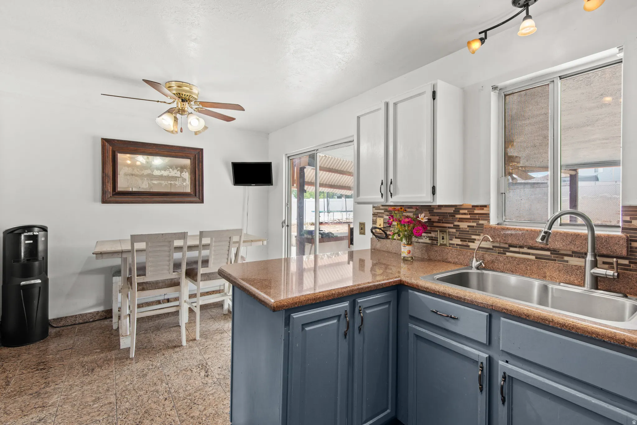 Kitchen featuring a dual basin sink, patterned tile backsplash, track lighting, and a ceiling fan