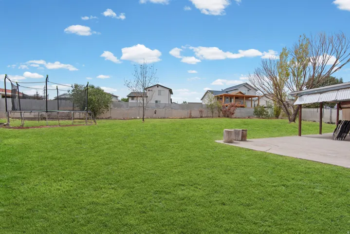 Expansive green lawn with a concrete patio and a covered outdoor structure