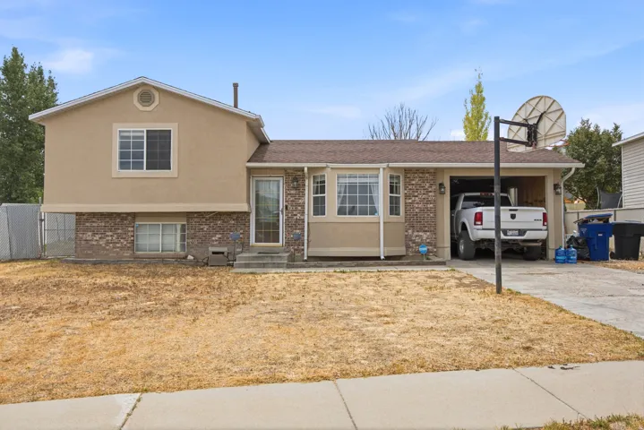 Split-level residence featuring a brick and stucco facade, an attached garage, and a concrete driveway