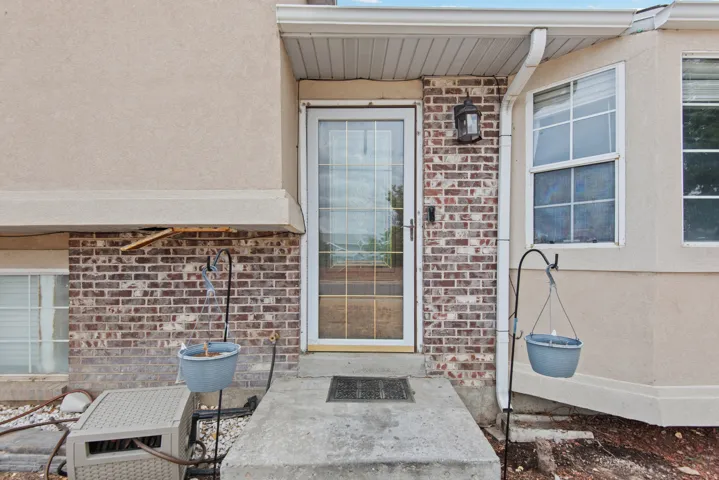 Brick and stucco exterior with multiple windows and a glass-paneled entry door