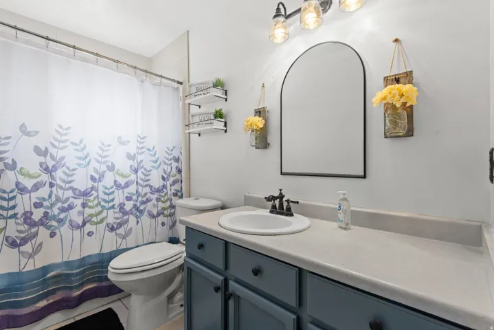 Bathroom featuring a single vanity with a white basin and dark hardware, light-toned countertop, and blue cabinetry