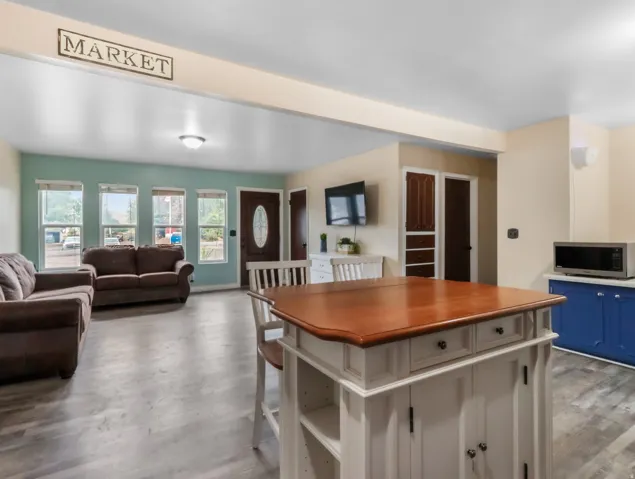 Open-concept living and dining area featuring a wood-finish island with storage drawers, hardwood dining table, and recessed ceiling lighting