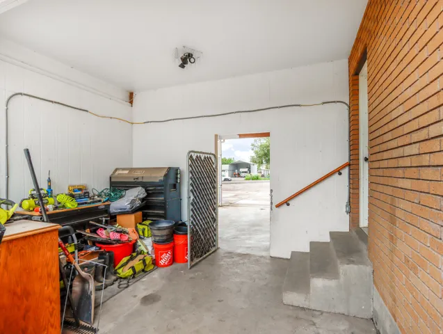 Concrete flooring, white paneled walls, exposed conduit, concrete steps, and a wooden handrail