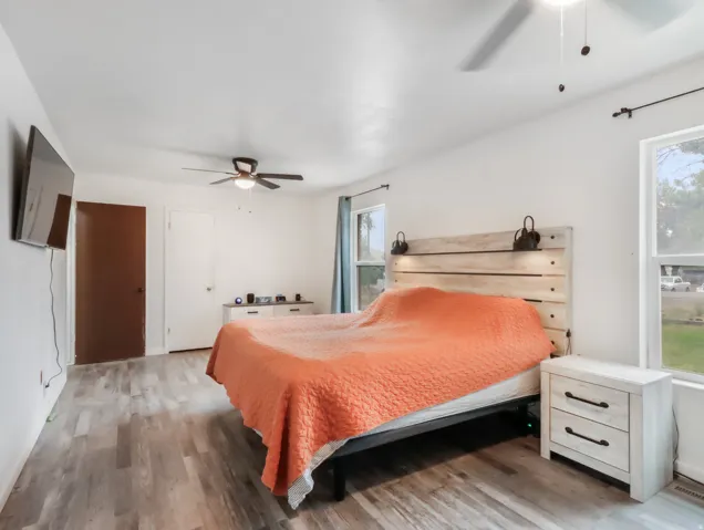 Wood-finish flooring with white walls and a ceiling fan
