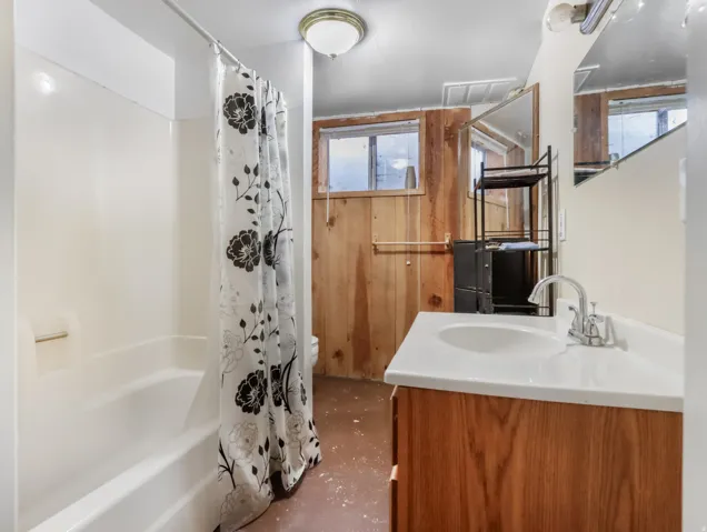 White vanity with integrated sink, chrome faucet, and wood-finish cabinetry