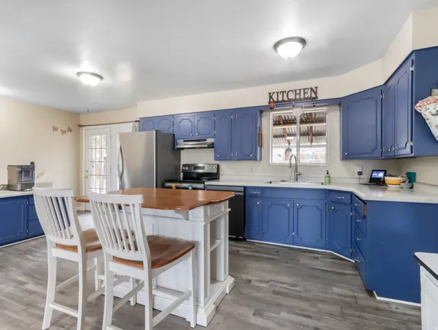 Kitchen featuring wood-finish flooring, blue cabinetry, light-toned countertops, and French doors