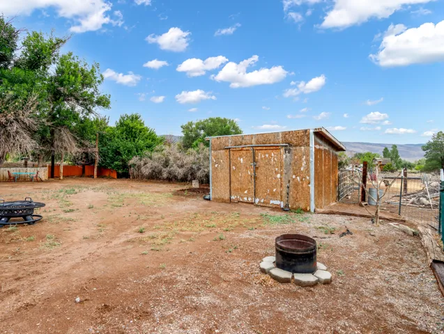 Expansive outdoor space featuring a utilitarian shed, perimeter fencing, and mature trees