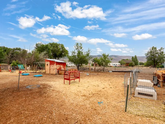 Expansive outdoor area featuring a red utility shed, mature trees, and a distant mountain backdrop