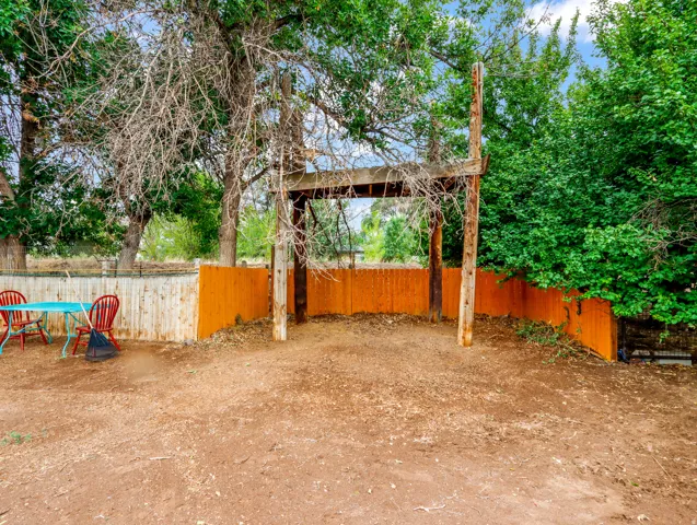 Wood beam arbor with privacy fencing and mature trees