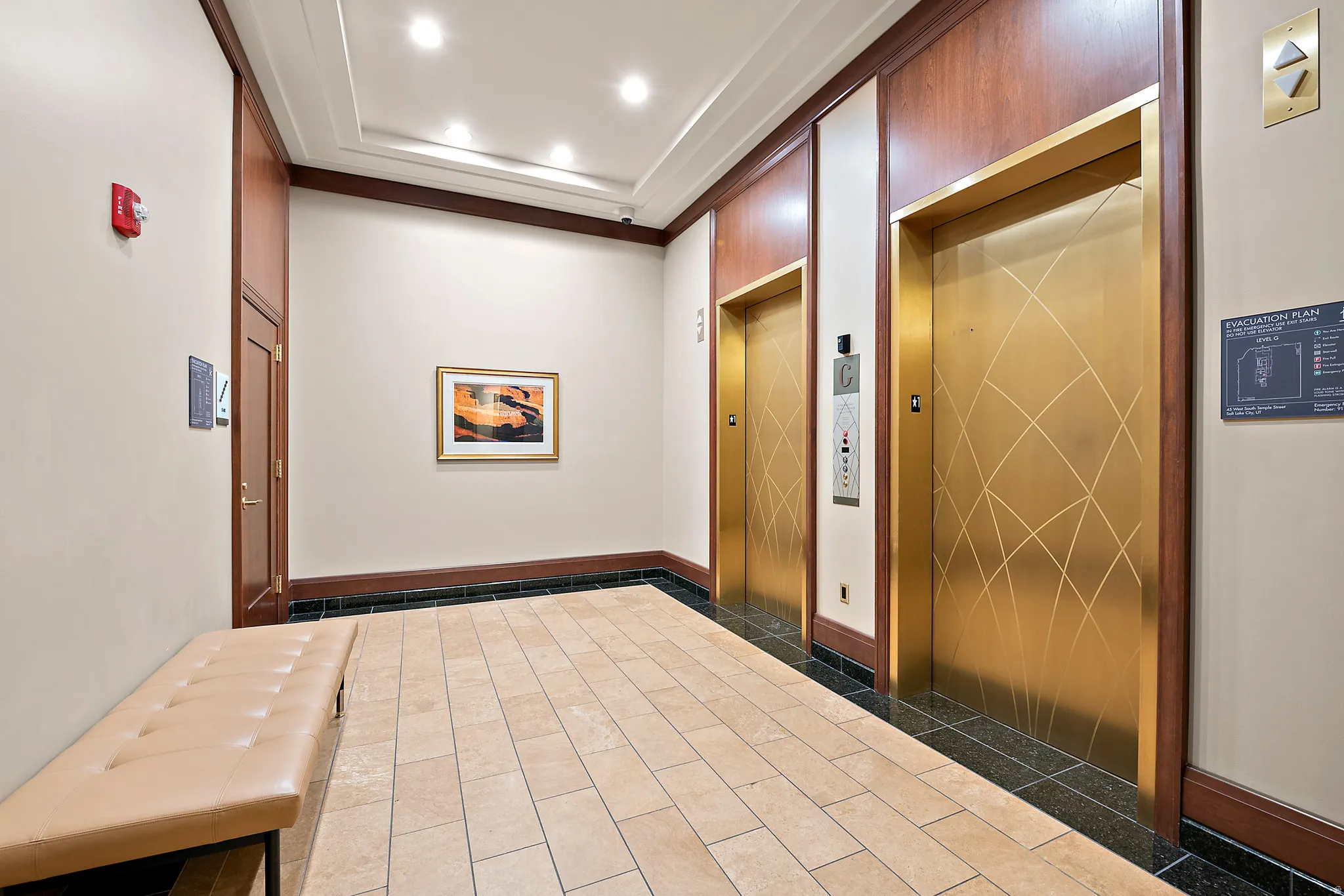 Two elevators with gold-tone doors, wood paneling, and tile flooring