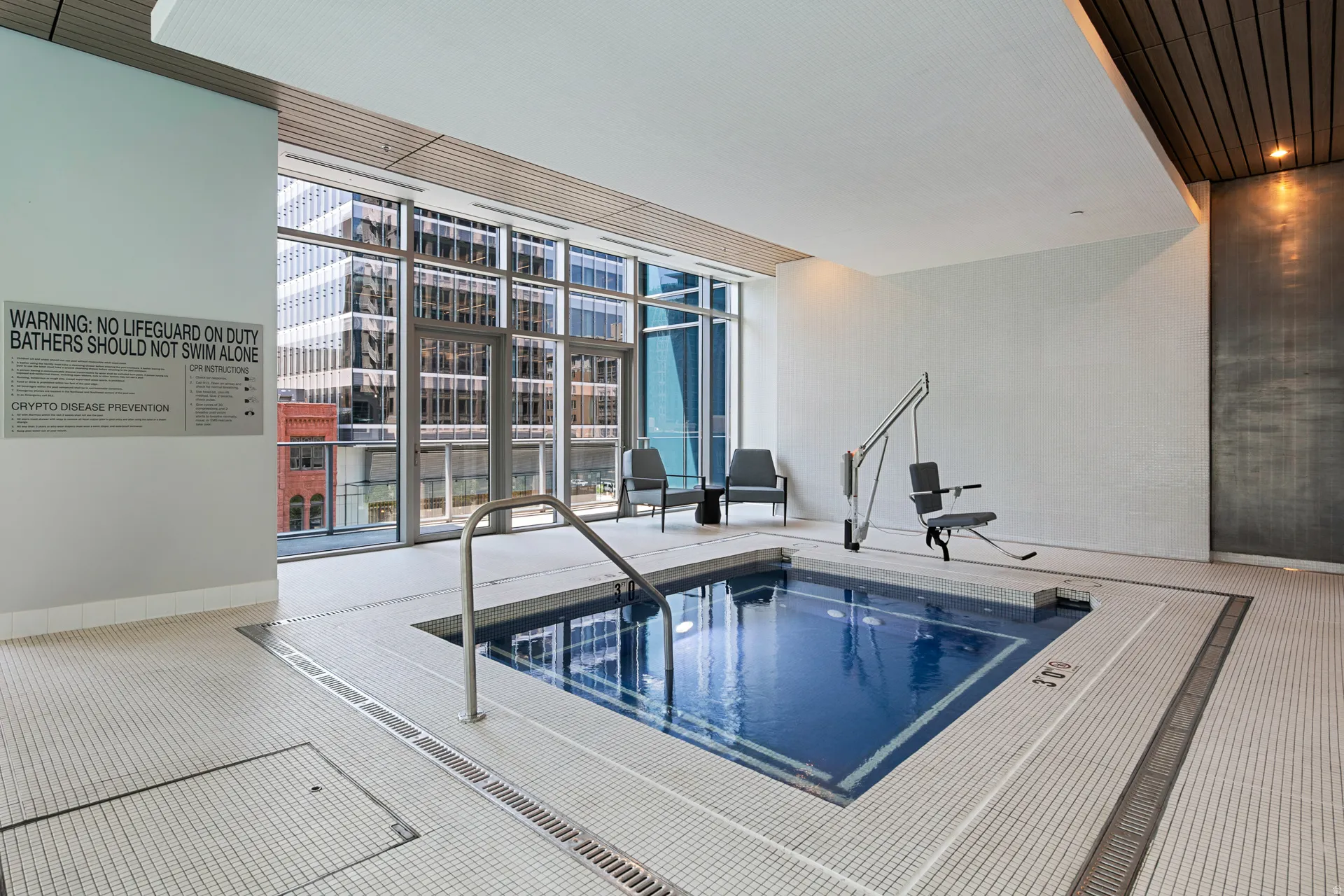 Indoor aquatic feature with expansive windows, tiled deck, and a wood-slat ceiling accent