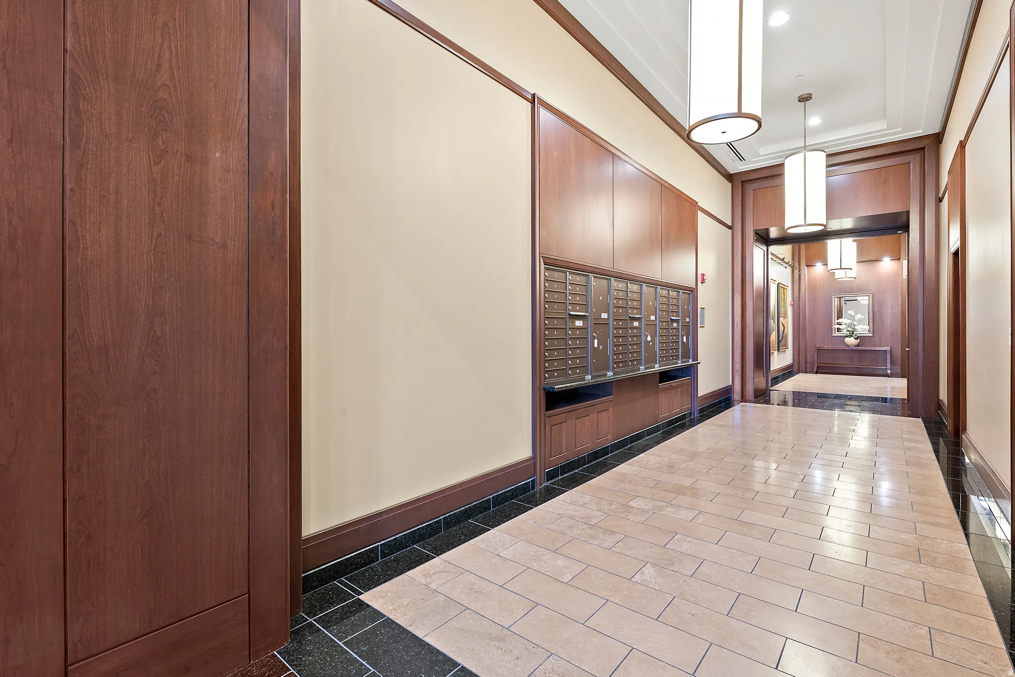 Entryway featuring rich wood paneling, a full wall of mailboxes, and pendant lighting