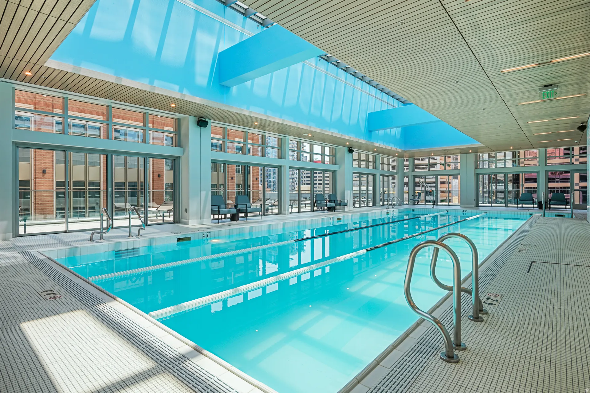 Indoor lap pool with a skylight, full-height windows, and recessed lighting
