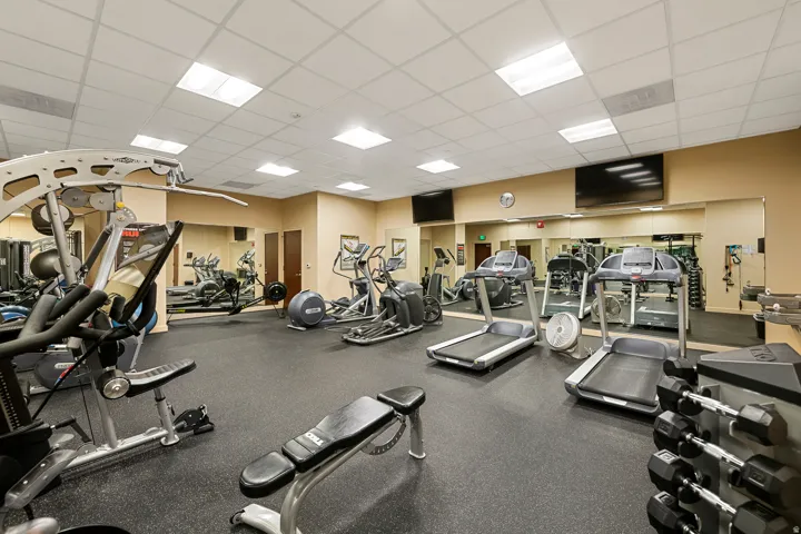 Fitness area featuring rubber flooring, mirrored walls, recessed lighting, and mounted televisions