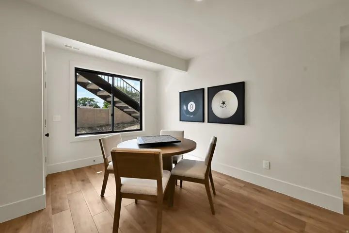 Wood-finish flooring, white walls, recessed lighting, and a large window with a black frame