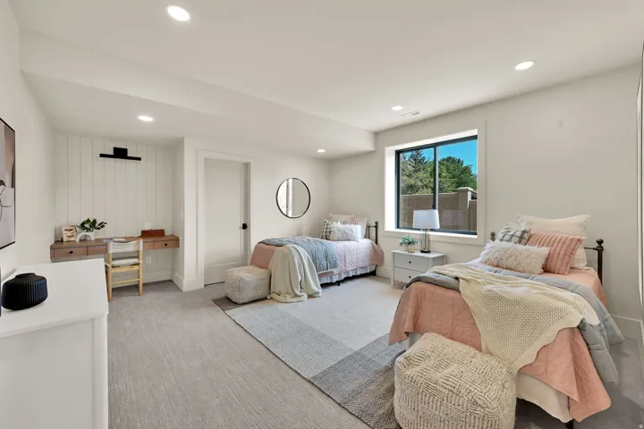 Recessed lighting, light-toned carpeting, a built-in desk with shiplap accent wall, a window, and a white door with black hardware