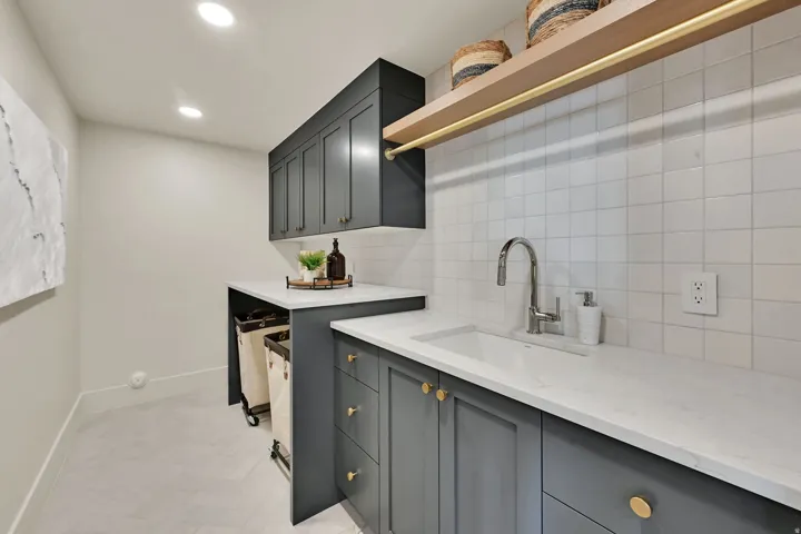 Second laundry with Recessed lighting, flat-panel cabinetry, light-toned countertops, ceramic tile backsplash, and a wall-mounted wood-finish shelf with a metal rod