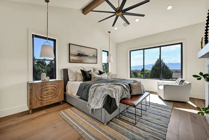 Primary bedroom with Vaulted ceiling with exposed wood beam, wood-finish flooring, recessed lighting, and a modern ceiling fan