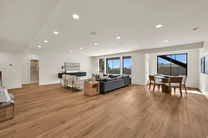 Expansive open-concept living area featuring wood-finish flooring, recessed lighting, and multiple large windows