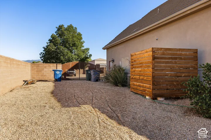 Gravel landscaping with a full-height block wall, and a wood-slat enclosure