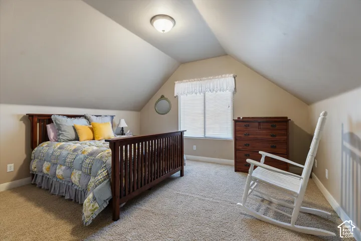 Sloped ceiling room featuring a window with blinds, recessed lighting, and carpeting