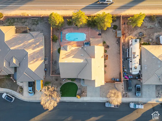 Residential property with a swimming pool, paved pool deck, and a front yard featuring artificial turf