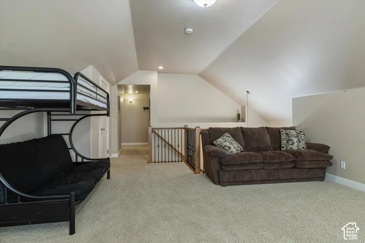 Carpeted loft space featuring sloped ceilings, recessed lighting, and a wood railing with wrought iron balusters