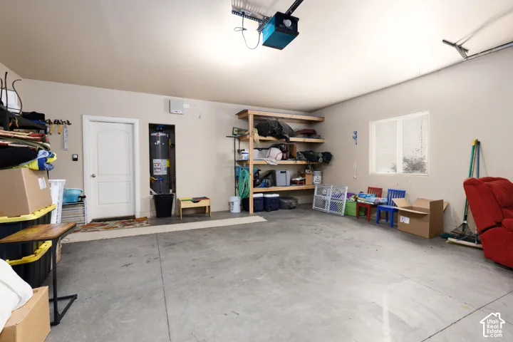 Spacious garage with concrete flooring, built-in shelving, a single window, and a white interior door