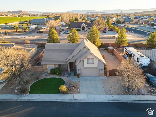 Pitched roofline with composite shingles, attached single-car garage, concrete driveway, and front yard with artificial turf