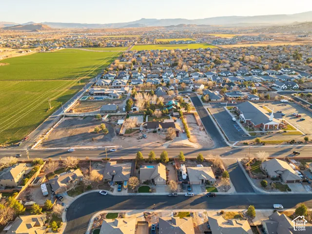 Expansive land parcel with surrounding residential properties, paved roads, and distant mountain ranges