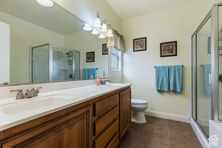 Double vanity with integrated sinks, brushed nickel fixtures, wood cabinetry, and a walk-in shower with a glass enclosure