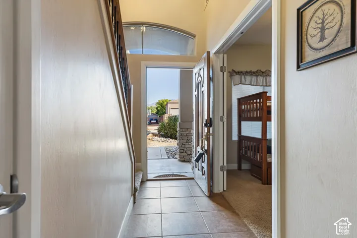 Tile flooring in the entryway with a wood-finish staircase railing and arched transom window